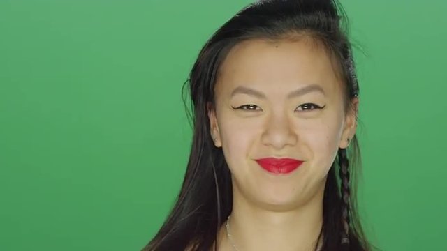 Young Asian woman smiling and dancing, on a green screen studio background