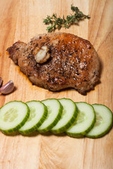 Fresh fried meat with thyme, garlic and cucumber on light wooden