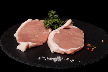Fresh meat steaks on black slate background. Selective focus