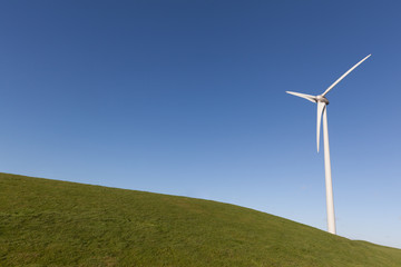 Fototapeta premium Close up of wind turine on a grass field with a clear blue sky