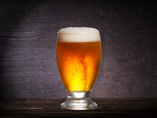 Glass of beer against dark wooden background, with copyspace