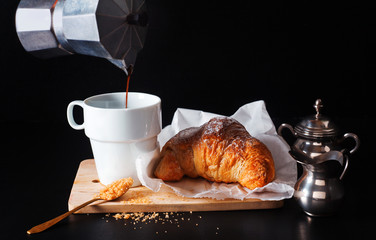 pouring coffee from the coffee maker. croissant. a healthy break