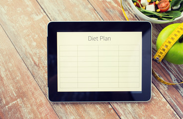 close up of diet plan on tablet pc and food