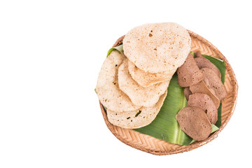 Freshly fried and dried raw fish crackers served on rattan tray with white background