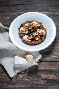 Melted brie with honey, pine nuts and walnuts on dark bread