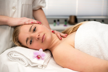 Fototapeta na wymiar Young woman lying on massage table receiving face massage. Beaut