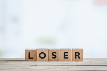 Loser sign on a wooden desk - obrazy, fototapety, plakaty