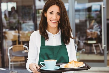 Waitress holding tray with coffee and croissant