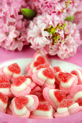 Obraz na płótnie Canvas Süßigkeiten Fruchtgummi in Herzform auf Teller mit Hyazinthen