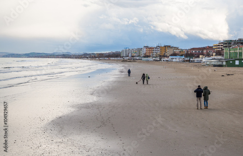 Gente passeggia lungo mare in una giornata piovosa