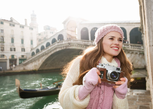 Happy woman tourist with retro photo camera near Rialto Bridge