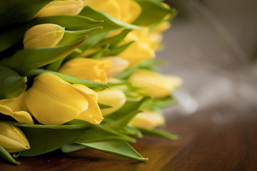 yellow tulips lying on wooden table