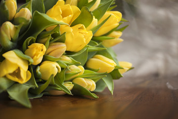 Obraz premium yellow tulips lying on wooden table