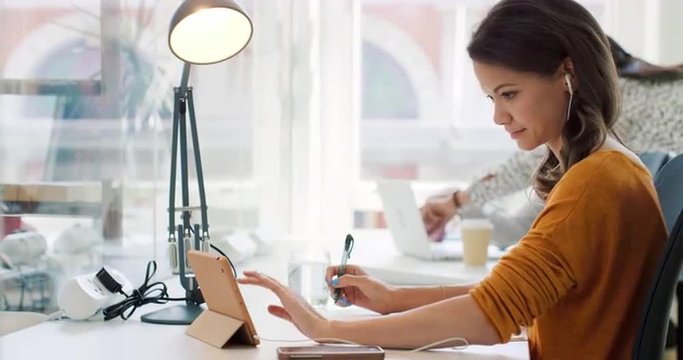 Mixed race team of young business people working in open plan office desk rows of computers in shared workspace bright natural light