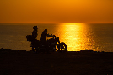 Fototapeta na wymiar Two people in the motorcycle at sunset on the Black Sea