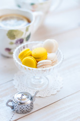 Colorful macaroons with cup of tea on color wooden table
