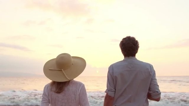 SLOW MOTION Retirement Vacation Concept, Happy Mature Retired Couple Enjoying Beautiful Sunset at the Beach
