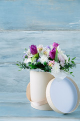 Beautiful summer bouquet of flowers in the hat box on the vintage blue wooden background copy space