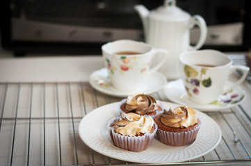 cream cheese and coffee cupcakes with tea pot on white wooden