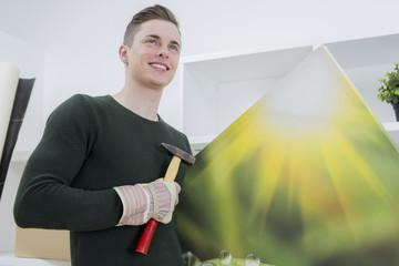 junger mann hängt ein bild auf