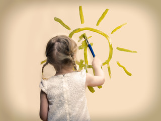 The child draws the sun on the wall. The concept - peace, security, peace of mind. A girl in a white dress with pigtails. retro, vintage processing. 