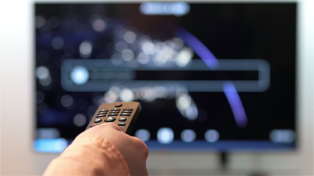 Woman hand changes the channels on the TV remote control.