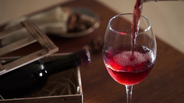 Pouring red wine into the glass and wooden background