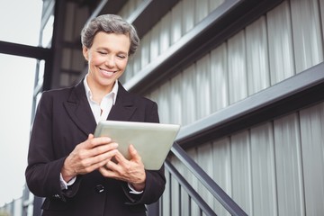 Businesswoman smiling while looking in digital tablet