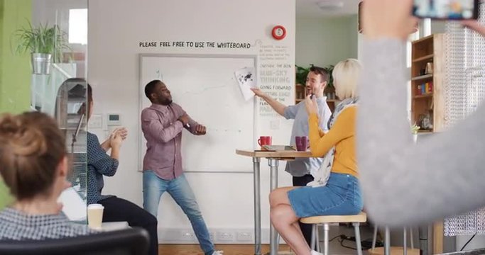 Crazy happy african american businessman dancing doing victory dance in team meeting celebrating success achievement