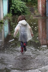 girl in rubber boots running through a puddle