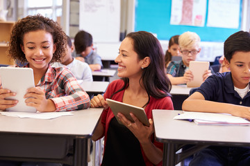 Teacher among kids with computers in elementary school class