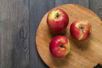 Top view of red apples on cutting board. Wooden table on kitchen.