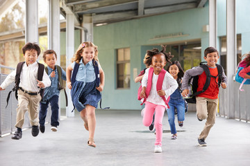 Group of elementary school kids running in a school corridor