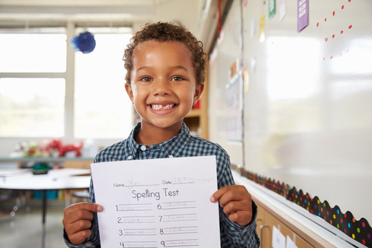 Portrait of elementary school boy holding up his test paper