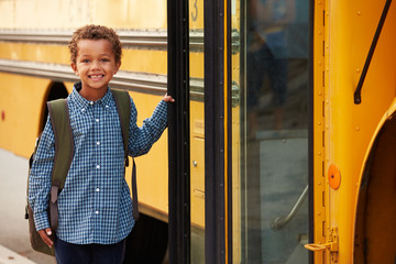 Elementary school boy getting onto a yellow school bus