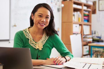 Portrait of female Asian teacher at her desk