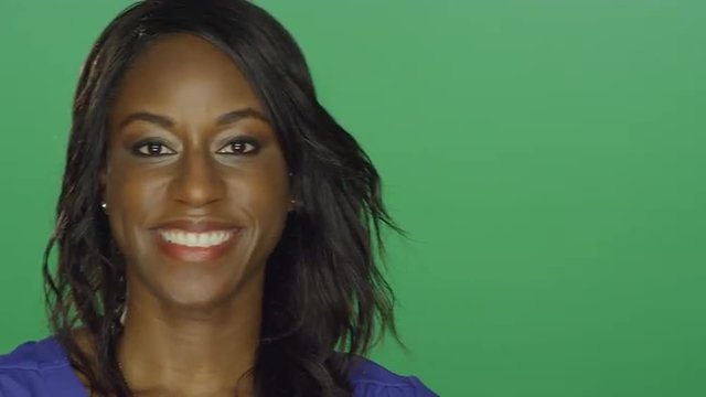 Beautiful African American woman making silly faces, on a green screen studio background