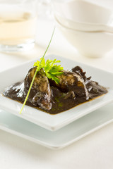 Squid served in its own ink on a clean white plate.