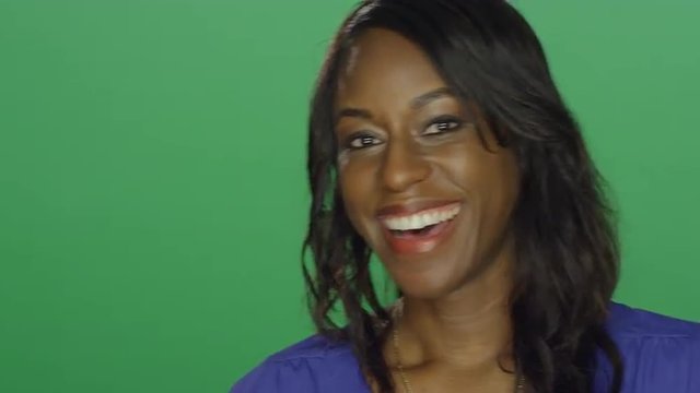 Beautiful African American woman laughing and smiling, on a green screen studio background