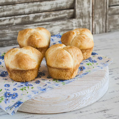 Homemade sweet brioches on a light rustic wood background
