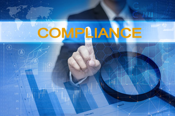 Businessman hand touching COMPLIANCE button on virtual screen
