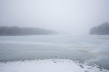 Thick fog at frozen lake landscape