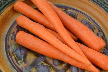 Whole fresh unpeeled carrots on plate