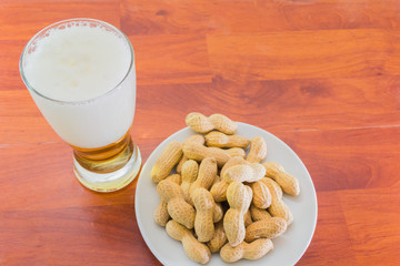 glass of beer and unpeeled peanuts