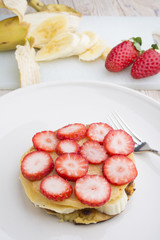 Stack of golden pancakes with strawberries, banana,