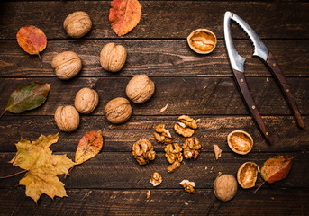 Walnut kernels whole walnuts and autumn leaves on dark rustic