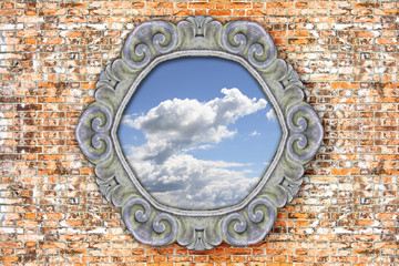 Old carved stone frame with the sky in the middle on brick wall