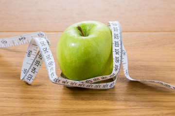 fresh green apple on a wooden table with measure close up