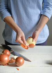 Woman hand cut fresh onion on white table
