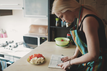 Young woman looking up in a recipes book